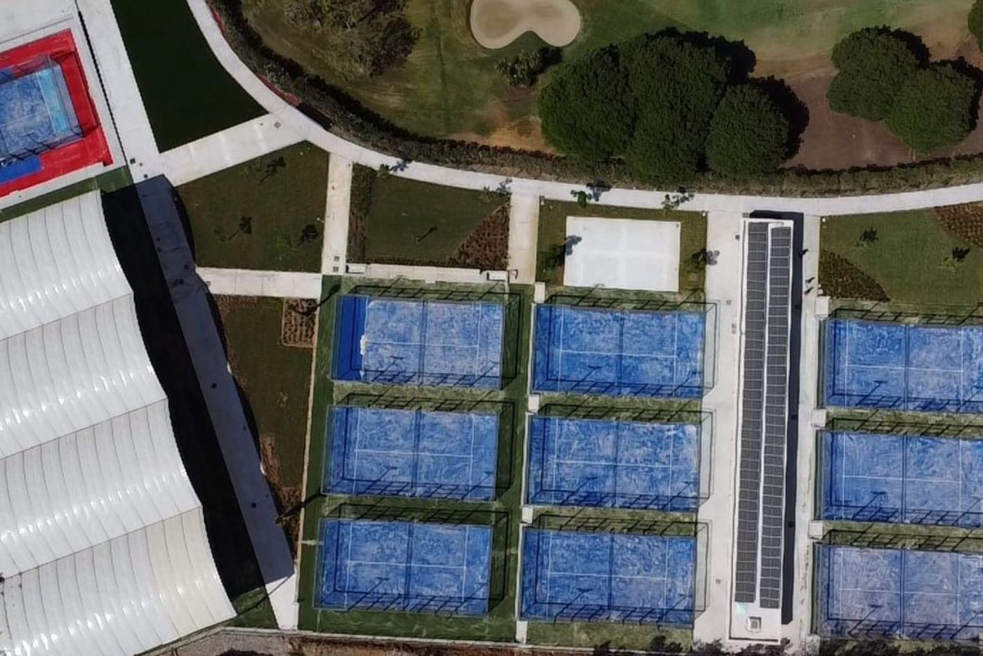 Aerial view in 2024: the same land with padel courts, a covered pavilion and landscaped paths.