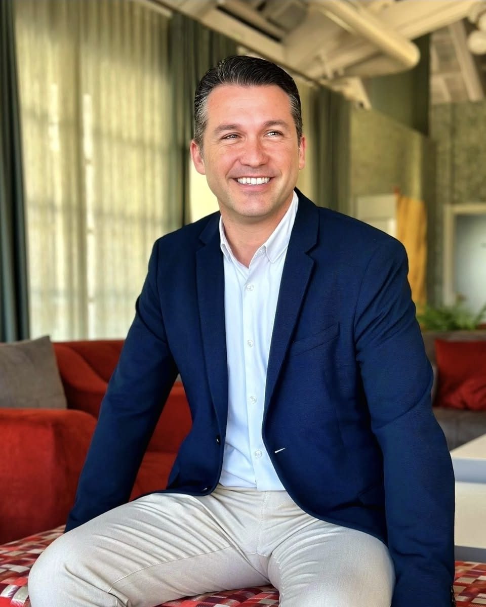 Julián Romaguera, smiling, seated in a hotel lounge in a navy blazer.